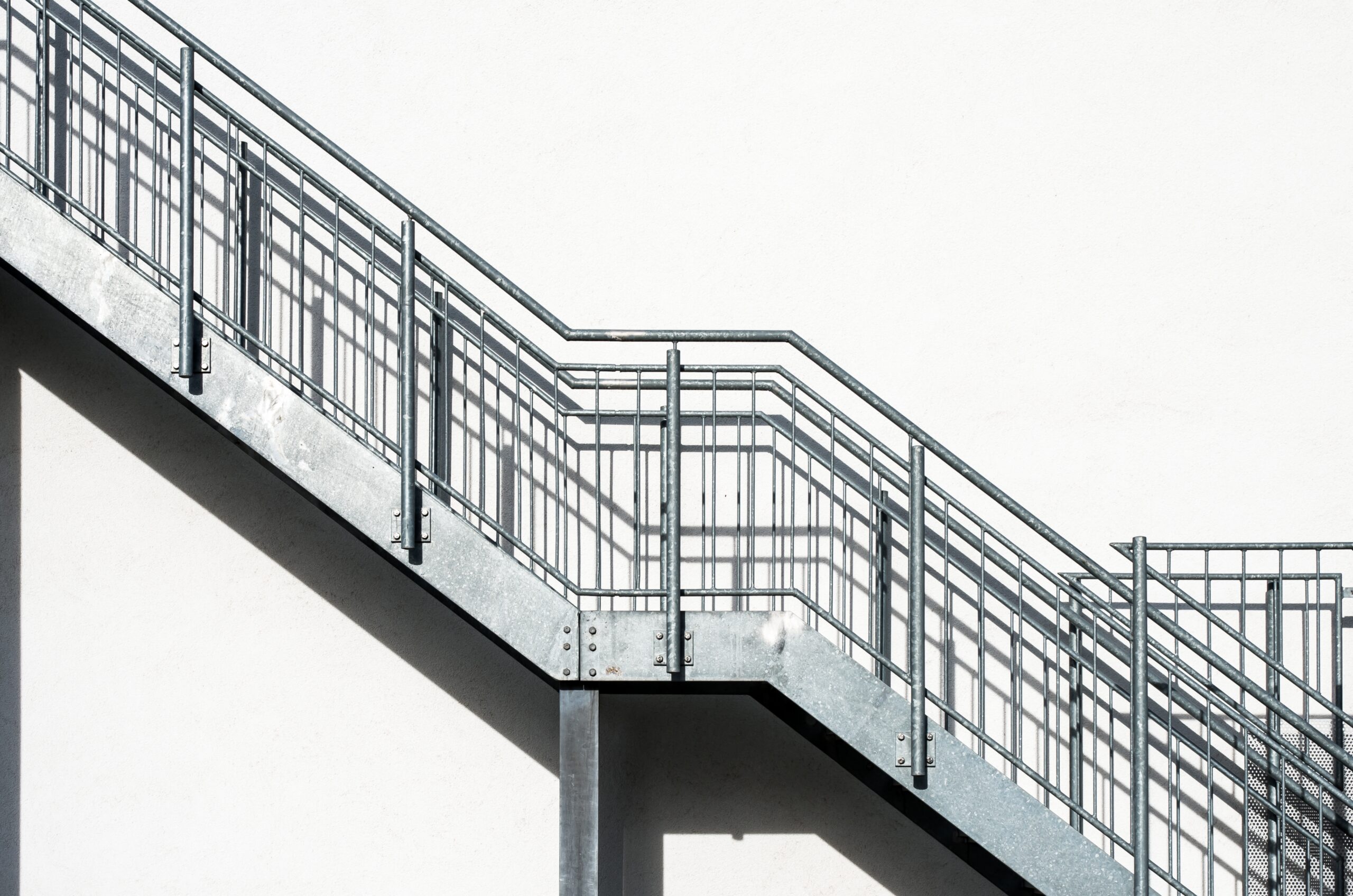 The metal stairs on a white building wall